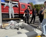 Feuerwehrleute zeigen Gästen Schutzanzüge für gefährliche Einsätze.