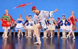     Mit rotem Schirm tritt eine Tänzerin vor das Ensemble von „Fairy Doll“.